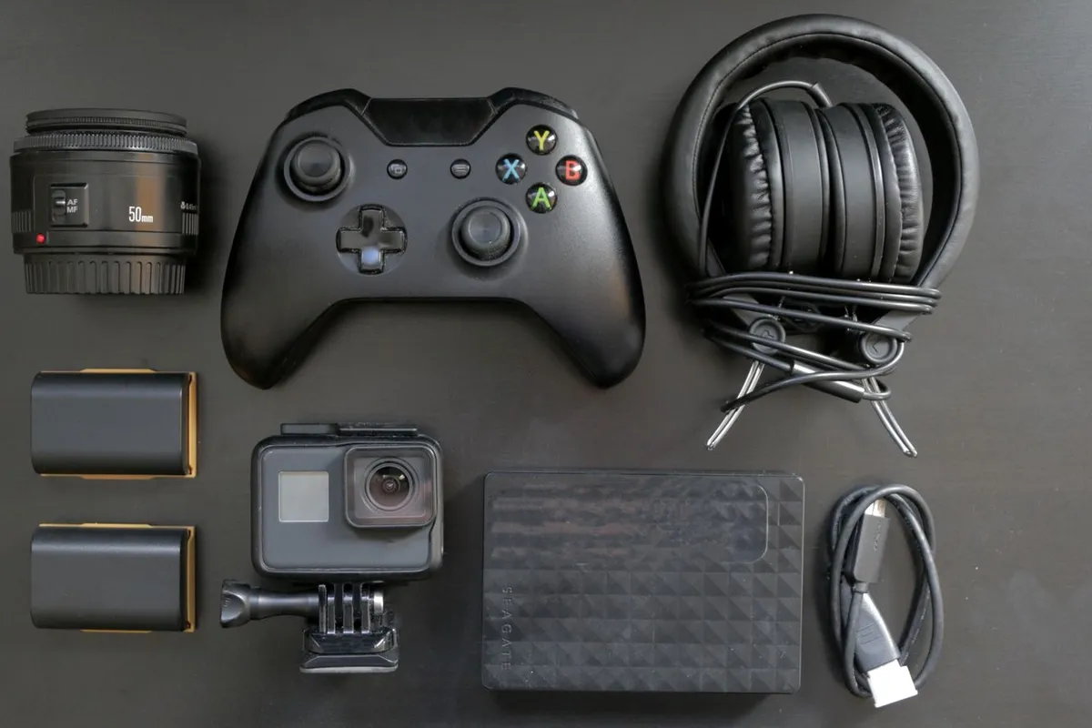 Game controller, headphones and camera laid out on a dark surface