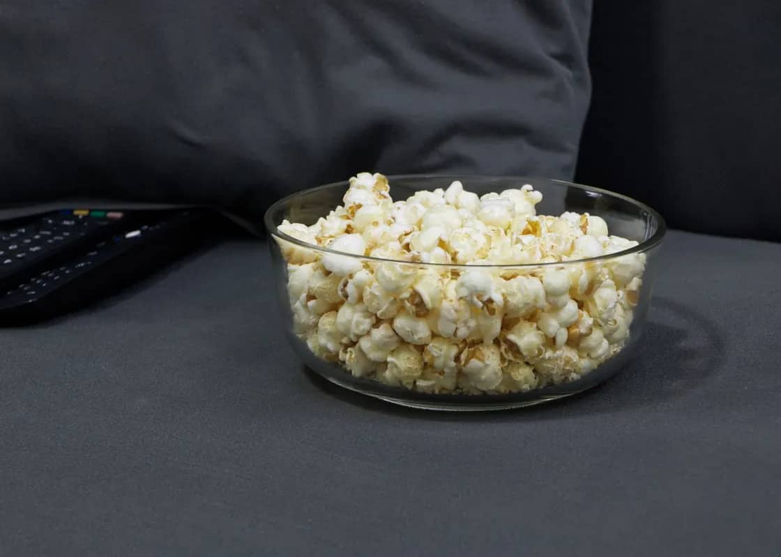Bowl of popcorn and a TV remote on a sofa